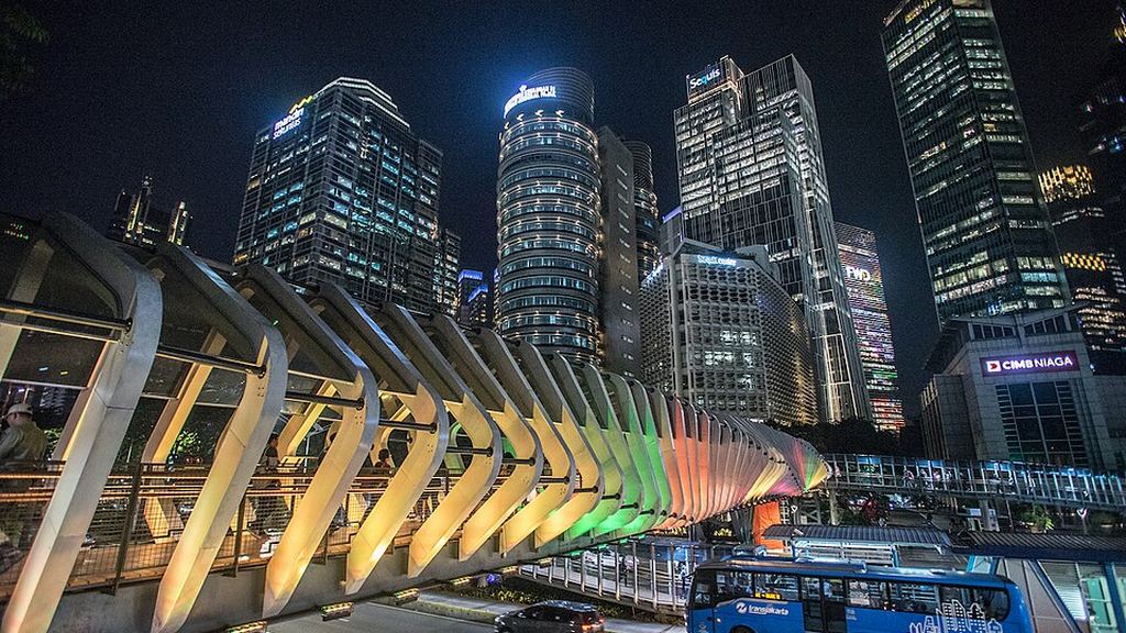 Office towers and a lit pedestrian bridge in Jakarta's Sudirman Central Business District at night