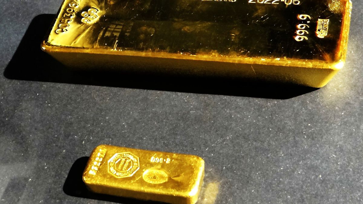 A large gold bar stamped 999.9 and a smaller gold ingot on a dark display surface